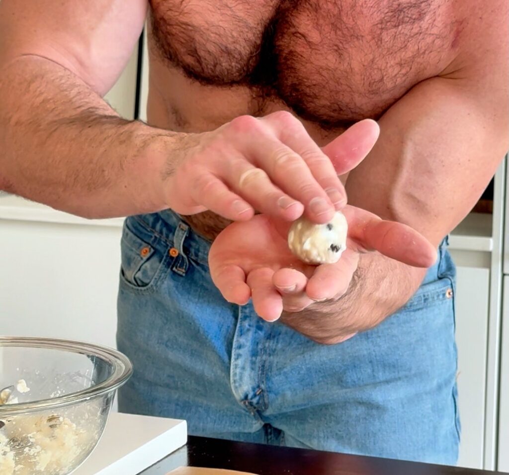 Rolling chocolate chip cottage cheese donut hole dough into balls