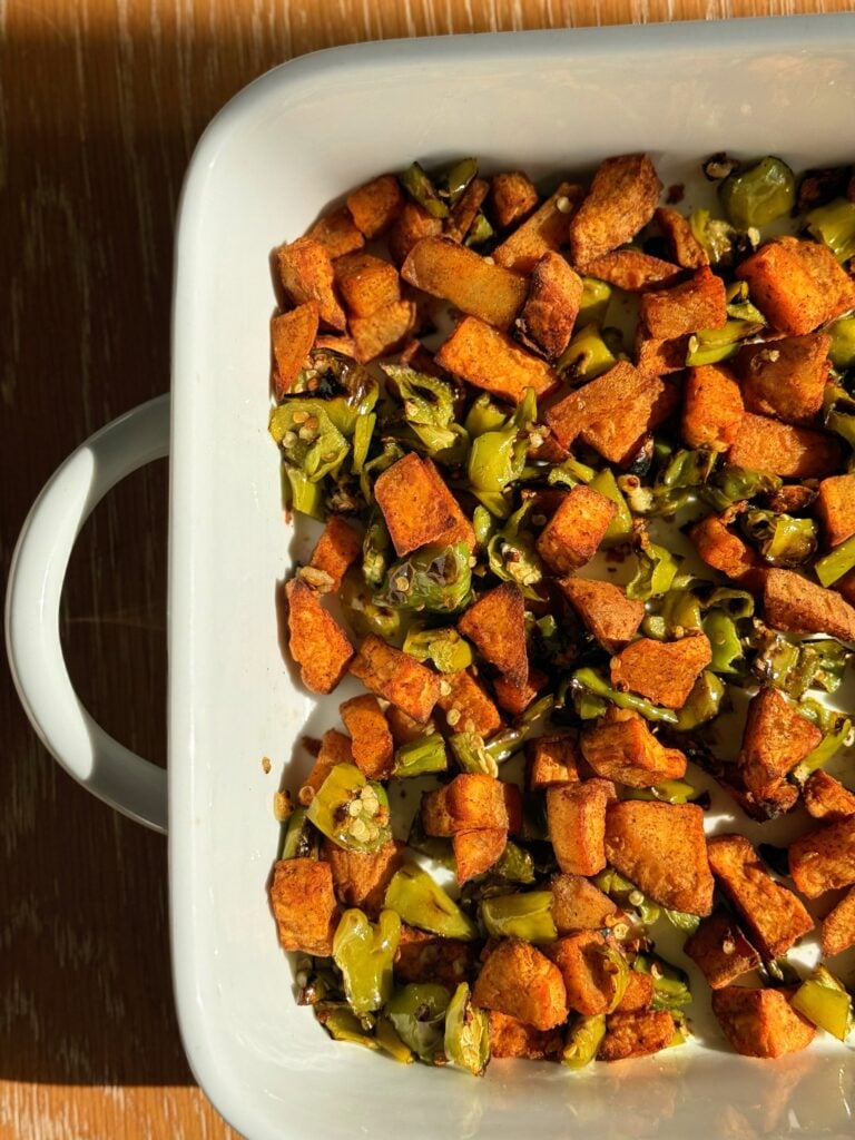 Sweet potato and shishito pepper hash topped with a poached egg, focusing on a balanced, high-fiber savory breakfast.