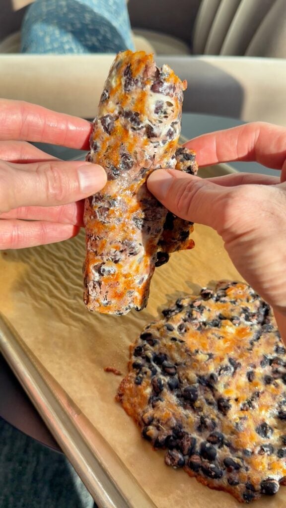 A rolled bean wrap sliced at an angle on a white plate, showing the melted cheese and whole beans inside.