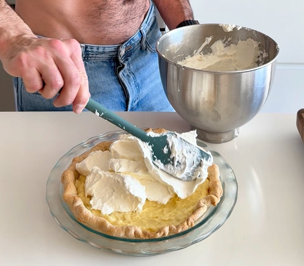 adding whipped cream to a coconut cream pie