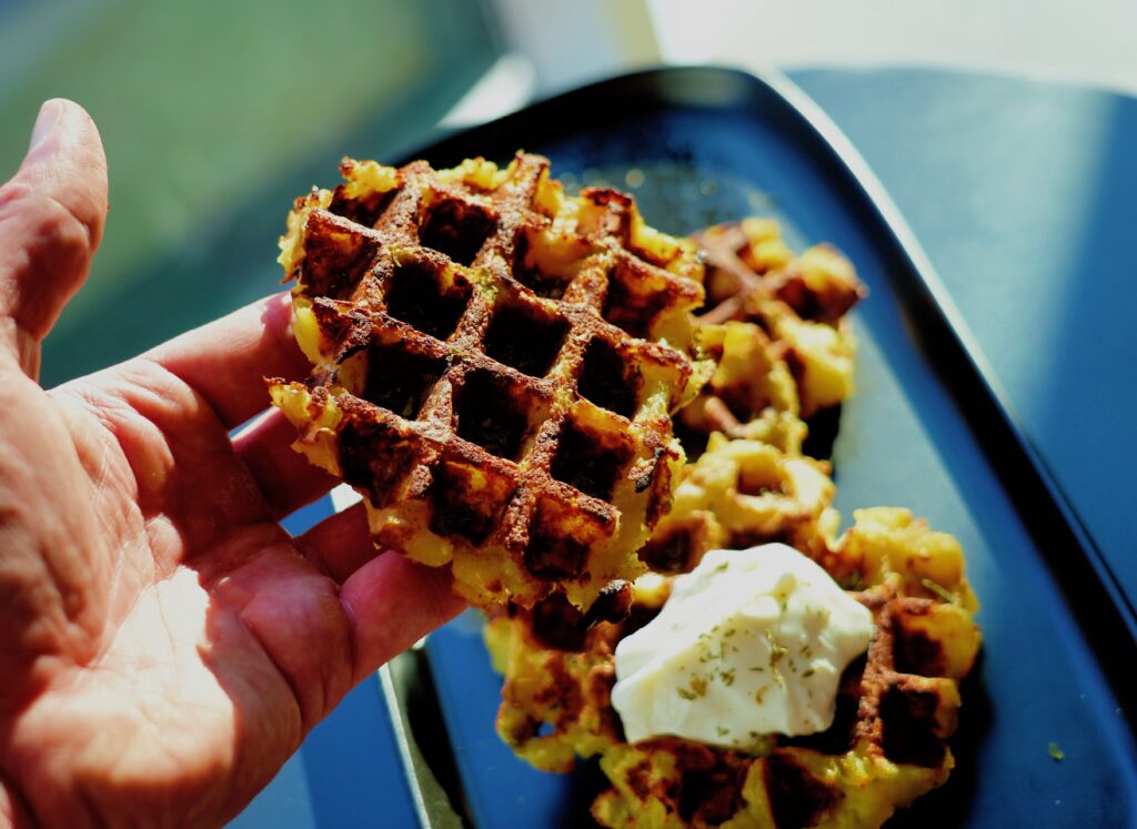 A potato waffle torn in half showing a soft mashed potato interior and crispy crust