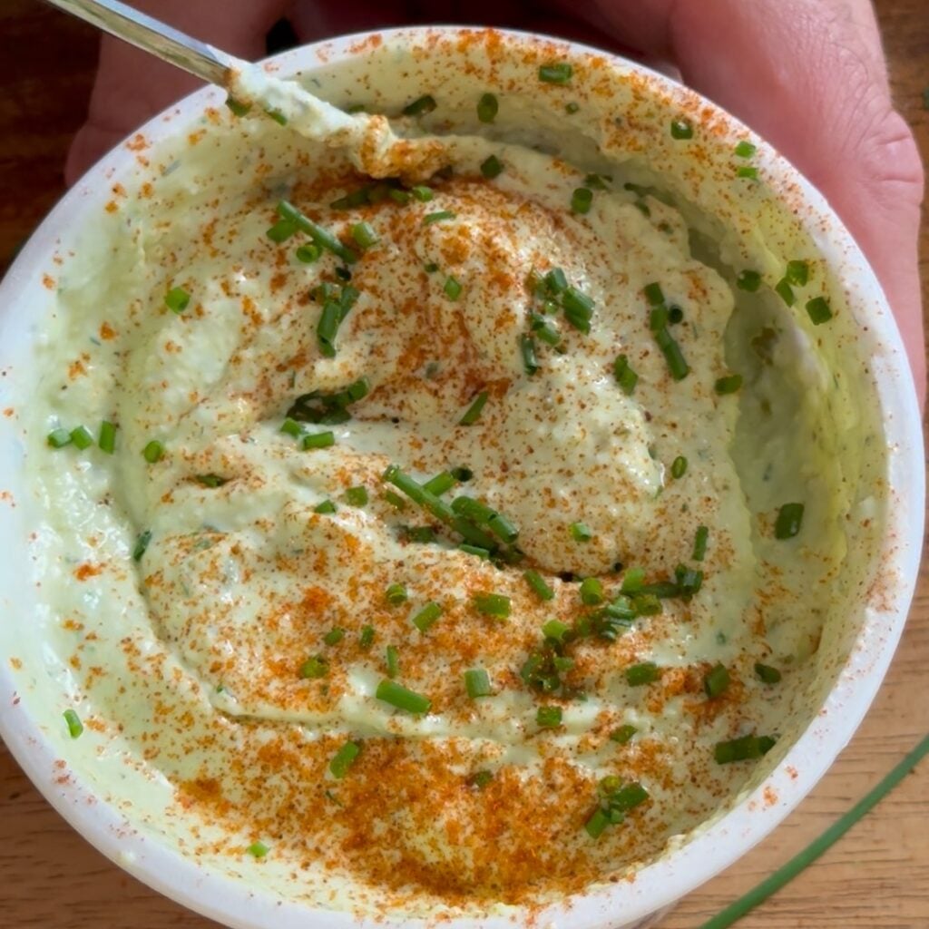 adding pickles and herbs smooth and creamy topped with paprika