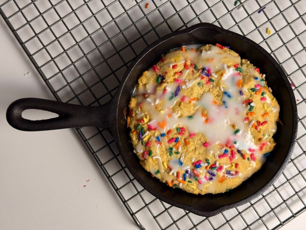 birthday cake protein cookie skillet with a spoon on counter