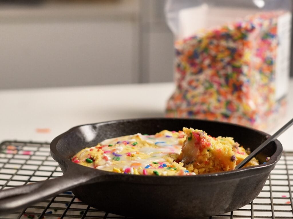 birthday cake protein cookie skillet with a spoon on table
