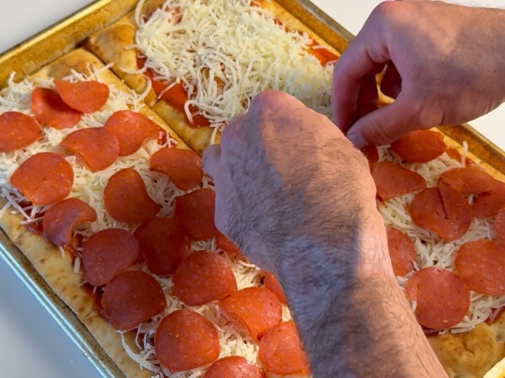 spreading pepperoni on healthy pepperoni pizza