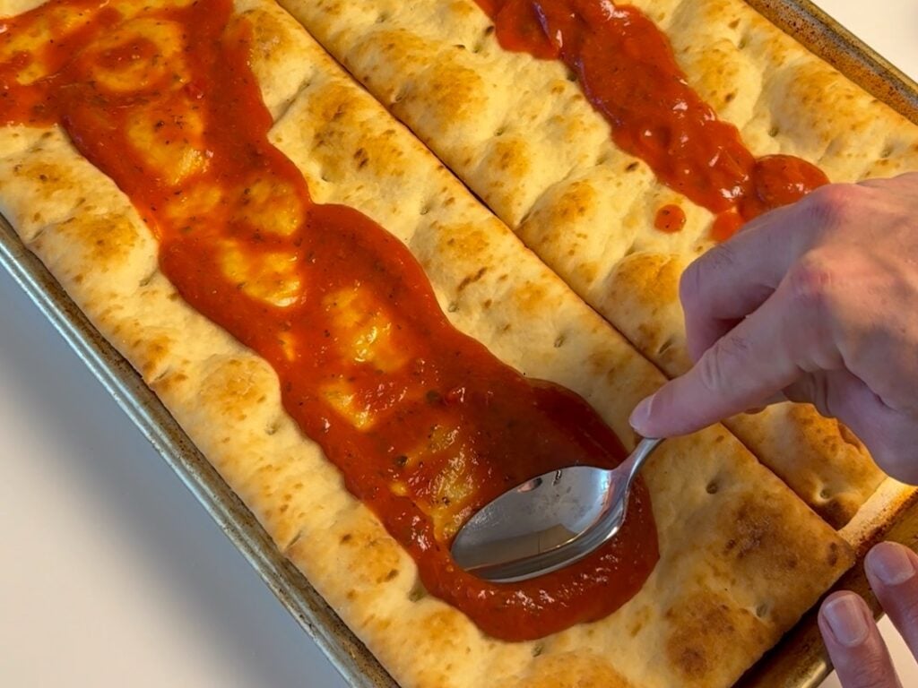 spreading sauce on healthy pepperoni pizza