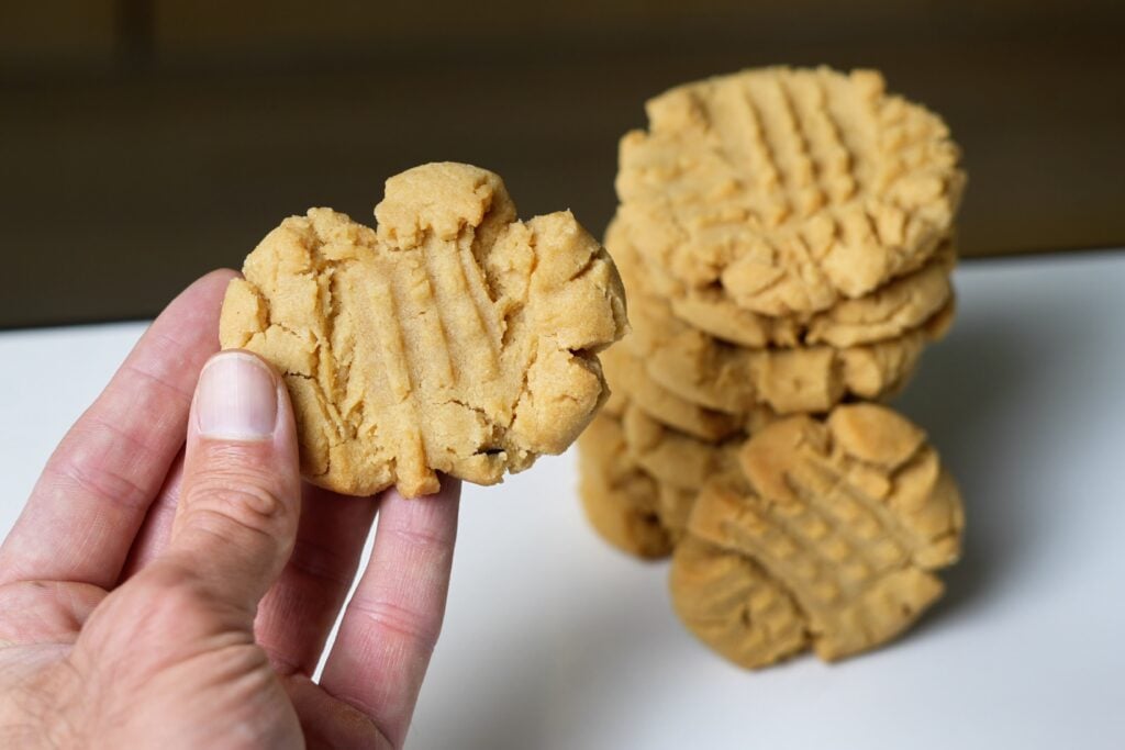 close up of stack of stack of old fashioned peanut butter cookies and in hand