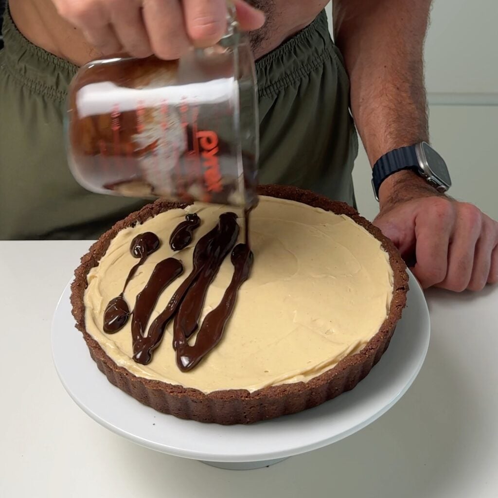 peanut butter tart with chocolate ganache adding ganache