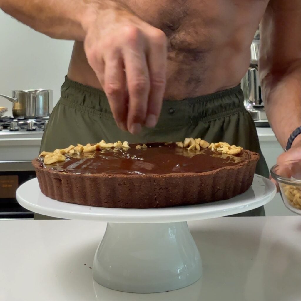 peanut butter tart with chocolate ganache adding peanuts