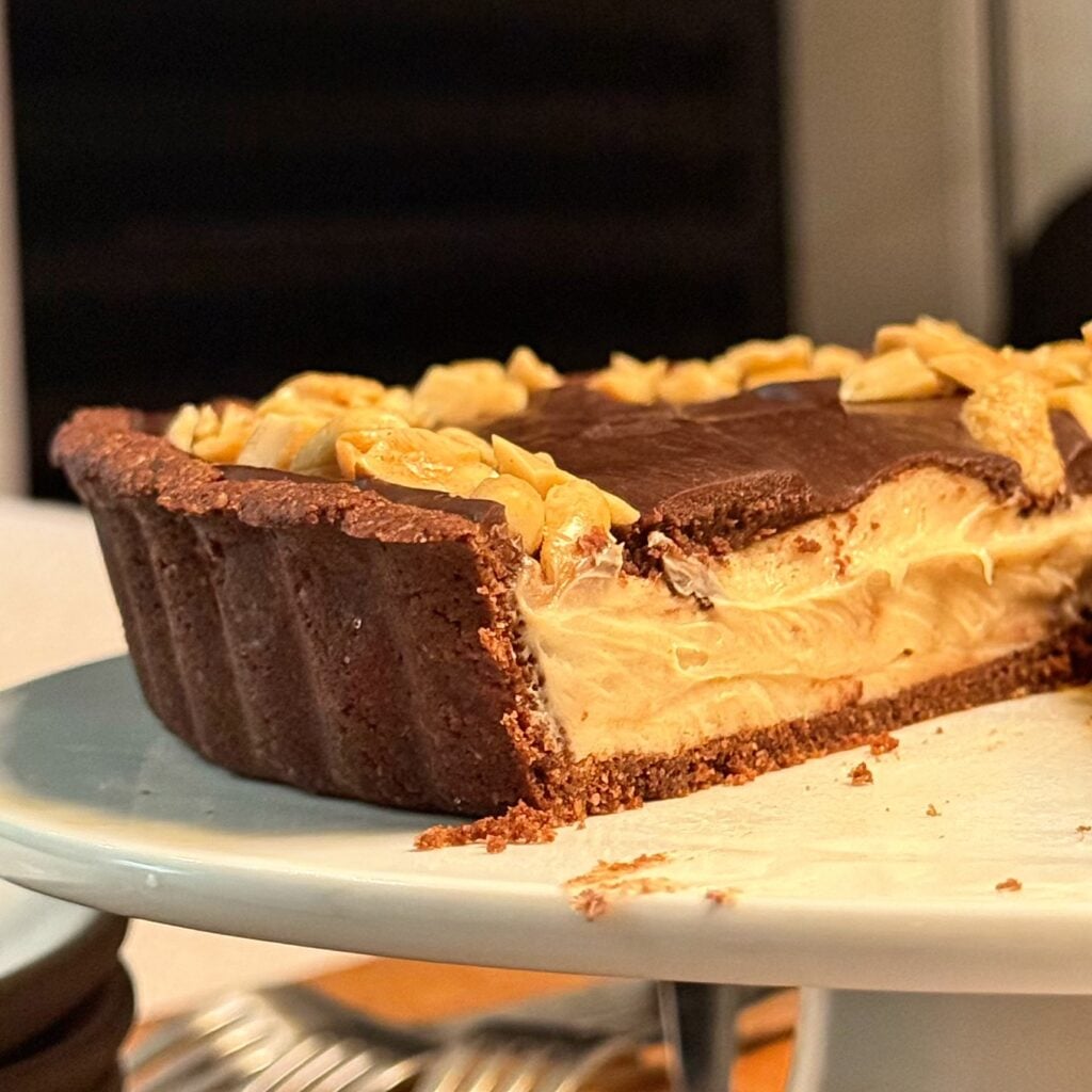 peanut butter tart with chocolate ganache on table sliced