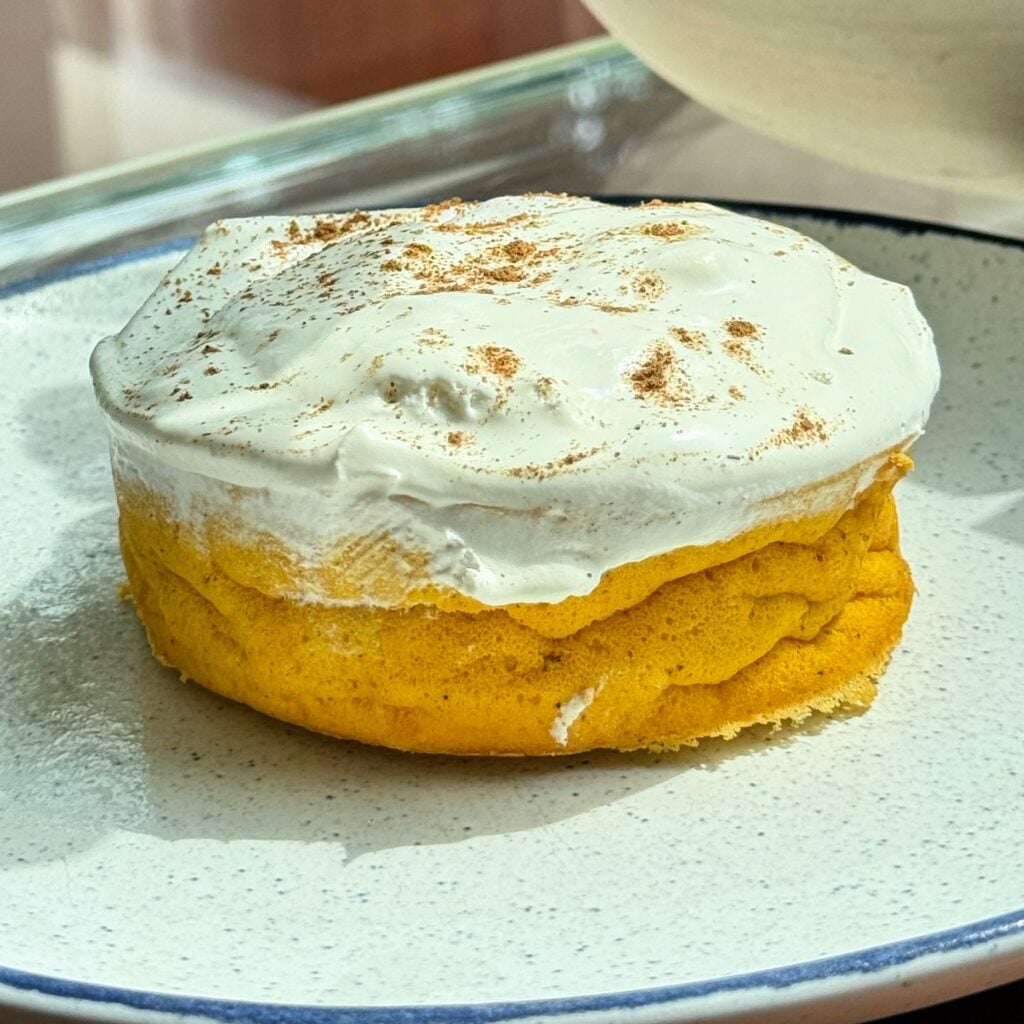 High protein pumpkin pie cheesecake topped with whipped cream and spices