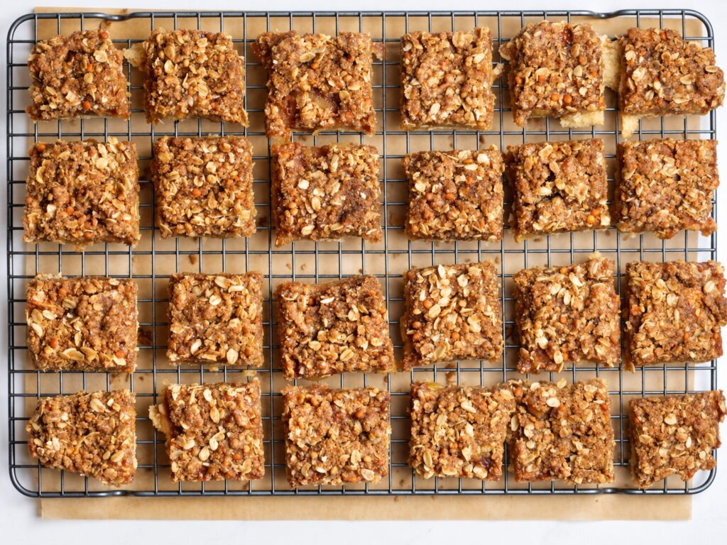 Cut gluten-free apple pie bars with oat streusel arranged on a cooling rack.