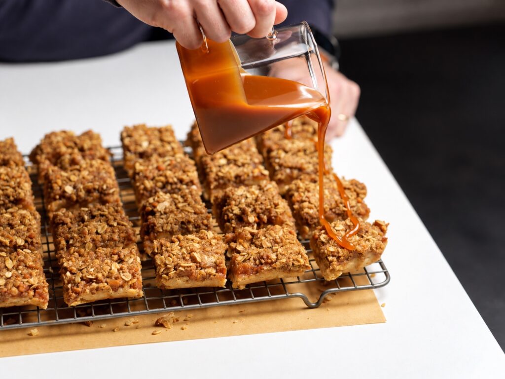 Close-up of salted caramel being poured over a gluten-free apple pie bar.