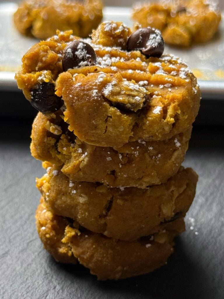 Stack of four soft pumpkin spice protein cookies with chocolate chips.