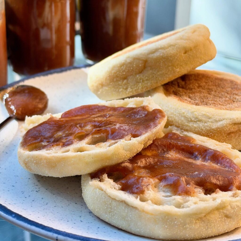 Homemade apple butter spread over toasted English muffin halves.