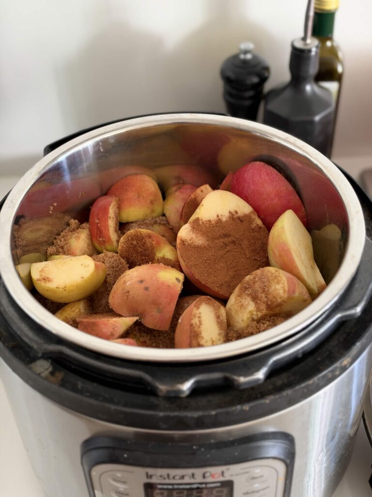 Chopped apples topped with brown sugar and cinnamon in a slow cooker.