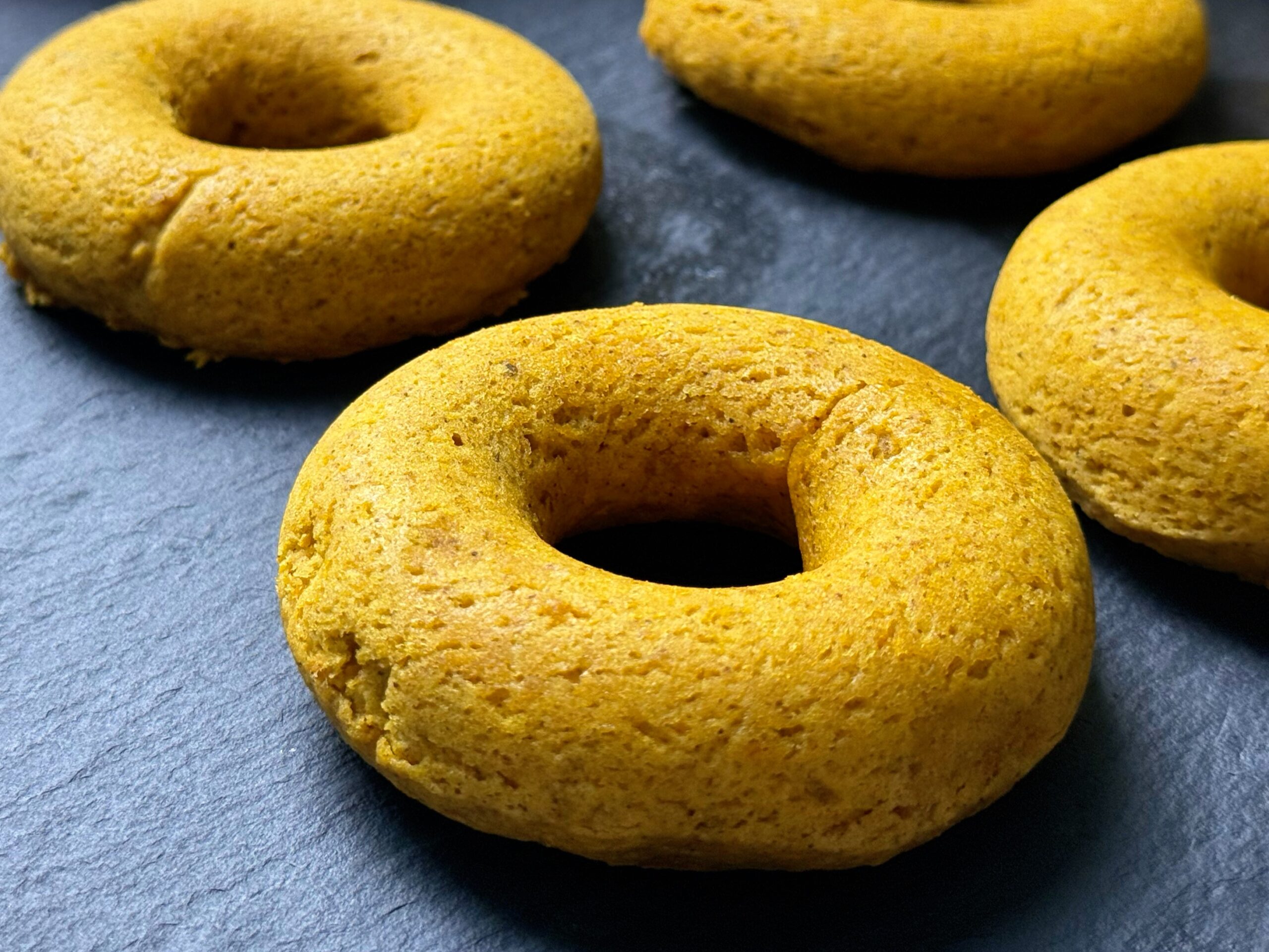 Close-up of baked pumpkin spice donuts on a dark slate board