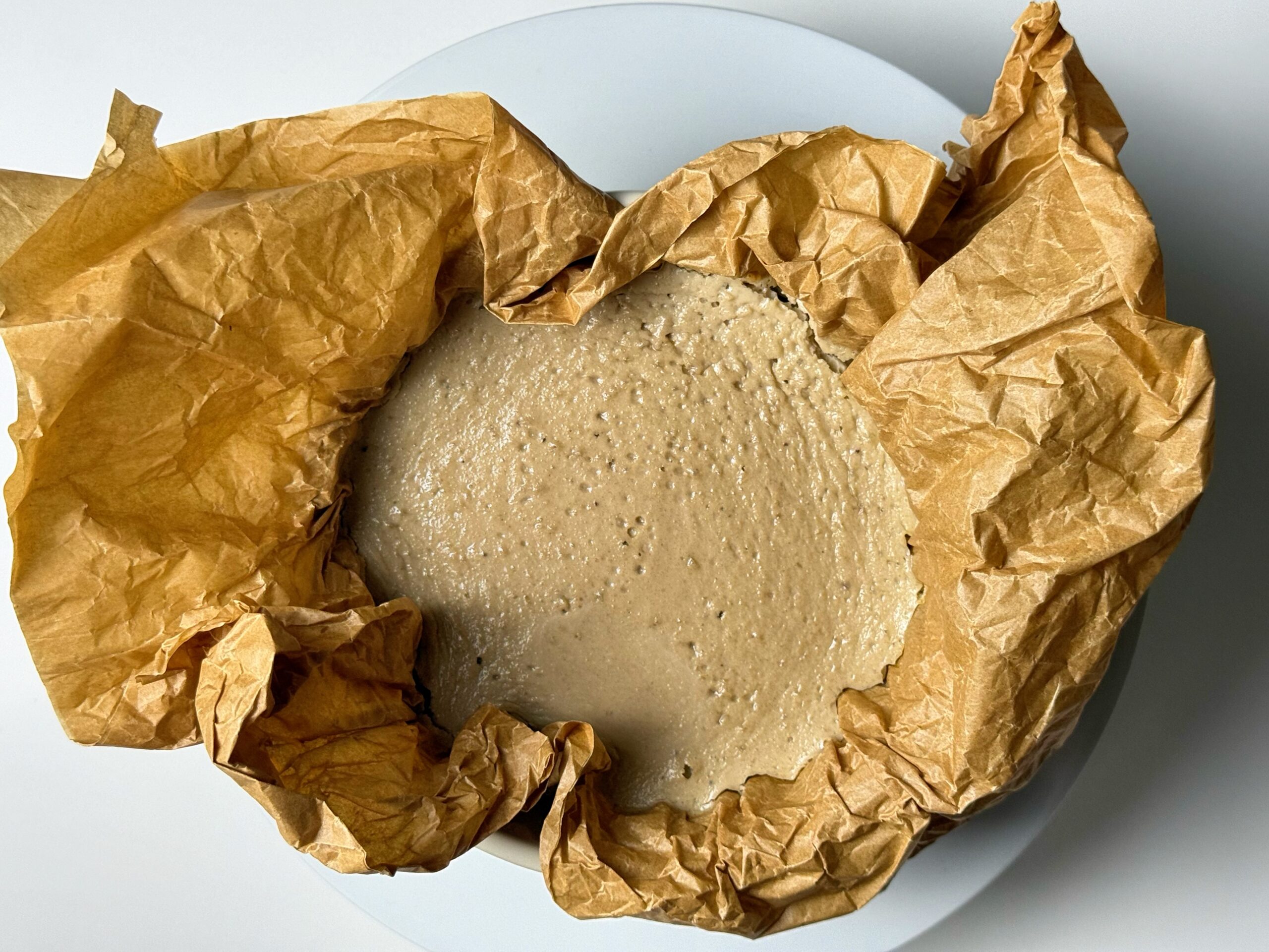 Overhead view of banana cream cheesecake resting in parchment paper before topping.