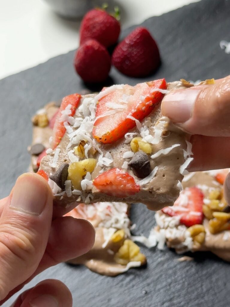 Close-up of chocolate Greek yogurt bark topped with strawberries, walnuts, coconut, and chocolate chips