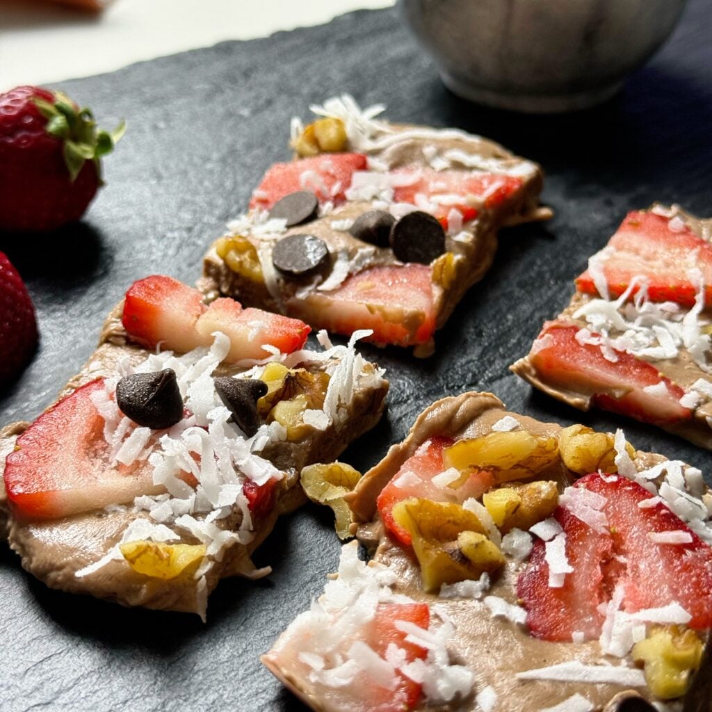 Close-up of chocolate Greek yogurt bark pieces with strawberries, walnuts, coconut, and chocolate chips