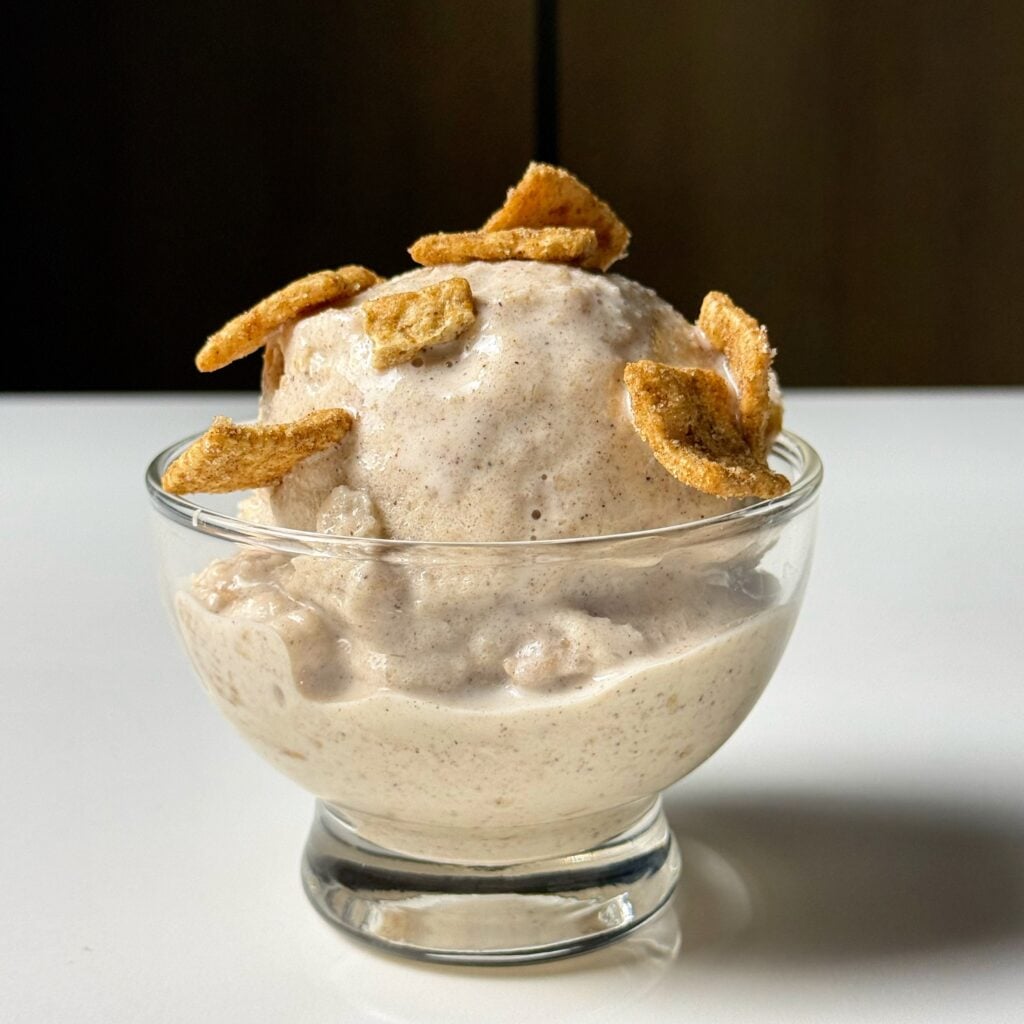 Close-up of high-protein Cinnamon Toast Crunch Ninja Creami topped with cereal pieces in a glass dessert bowl.
