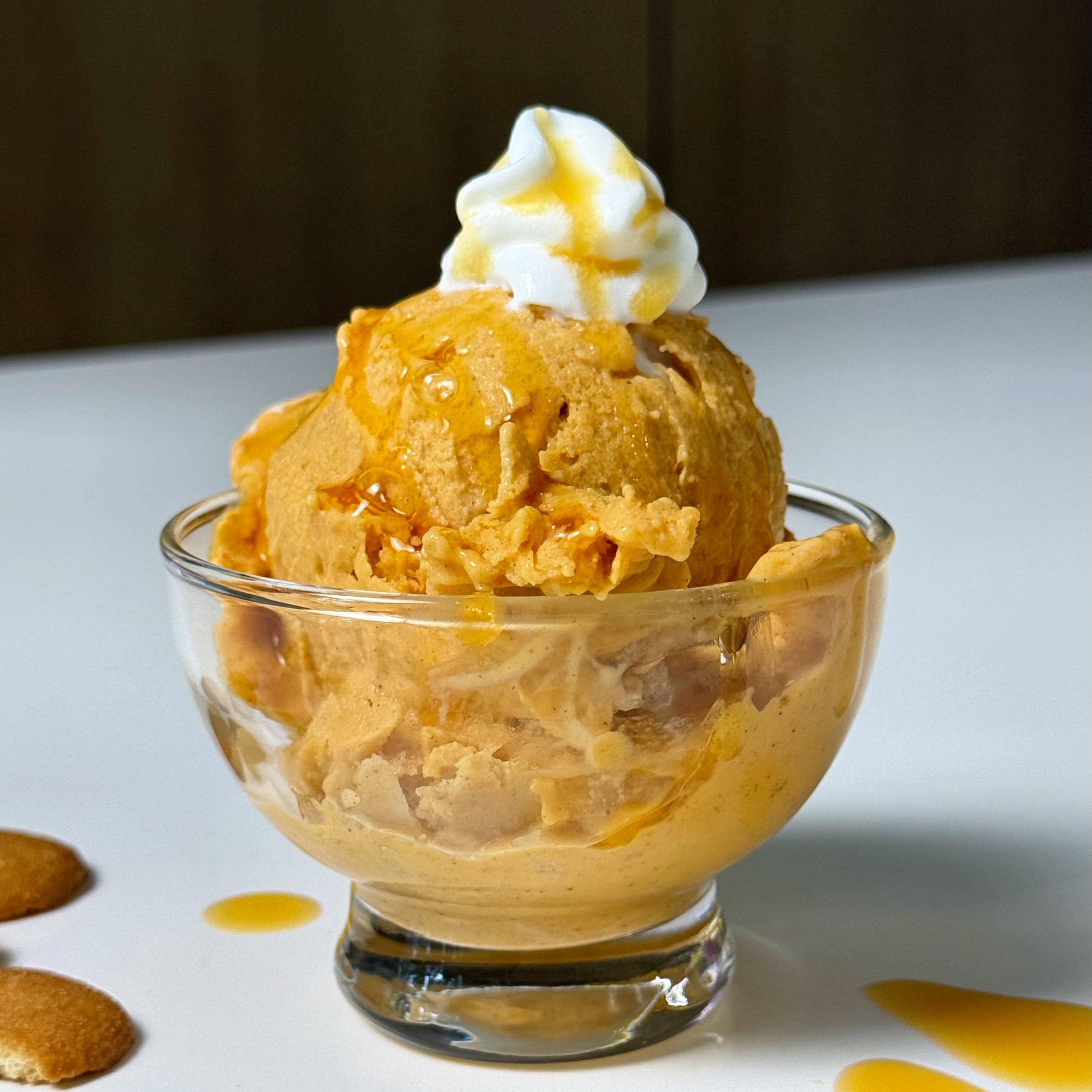 Scoop of high-protein pumpkin pie Ninja Creami topped with whipped cream and syrup