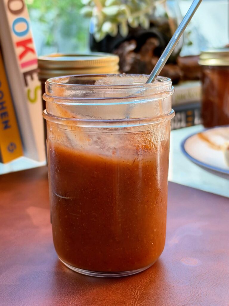A glass jar filled with smooth homemade apple butter.