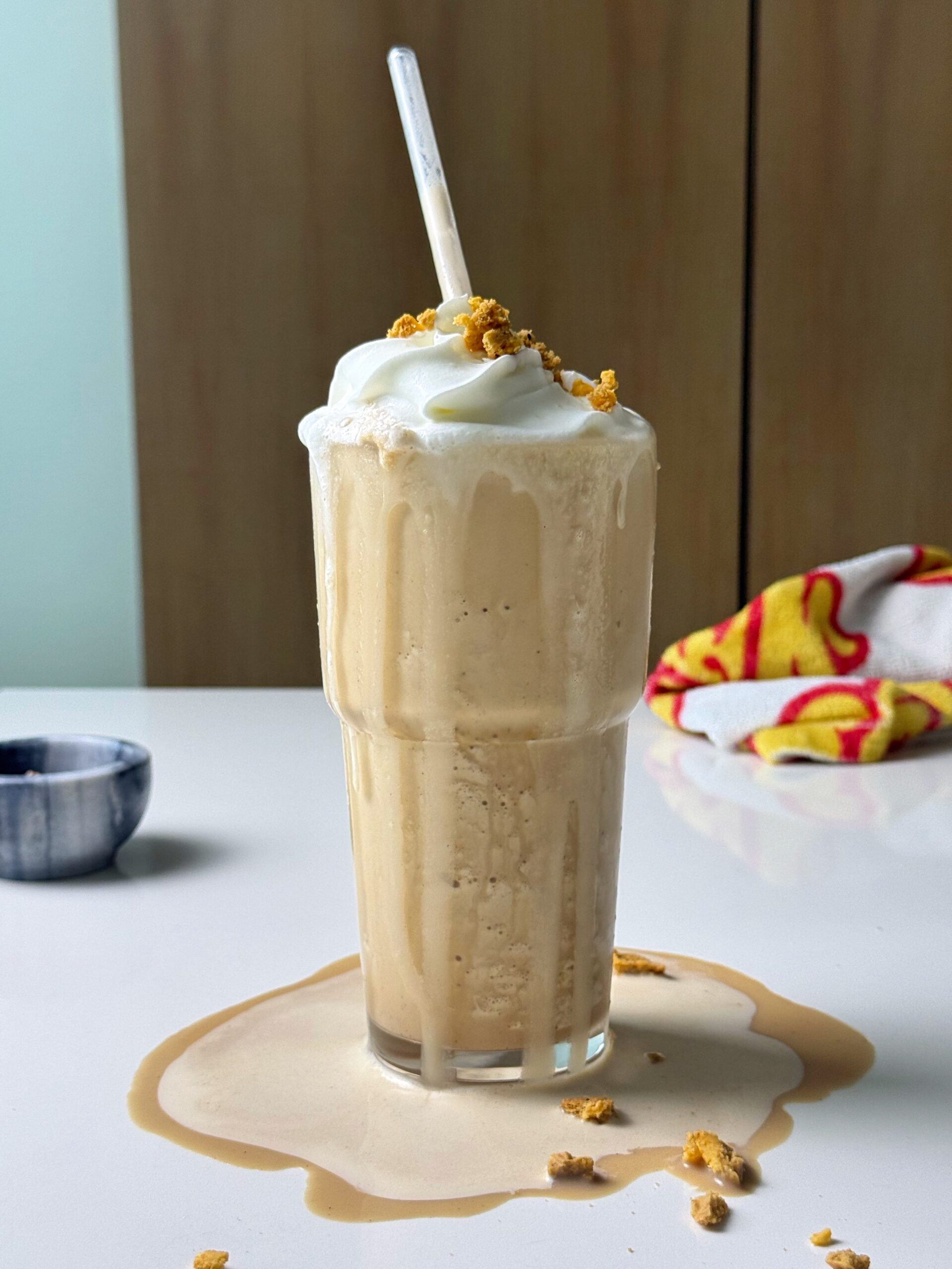 Tall glass of pumpkin spice protein frappé with whipped cream and cookie crumbs