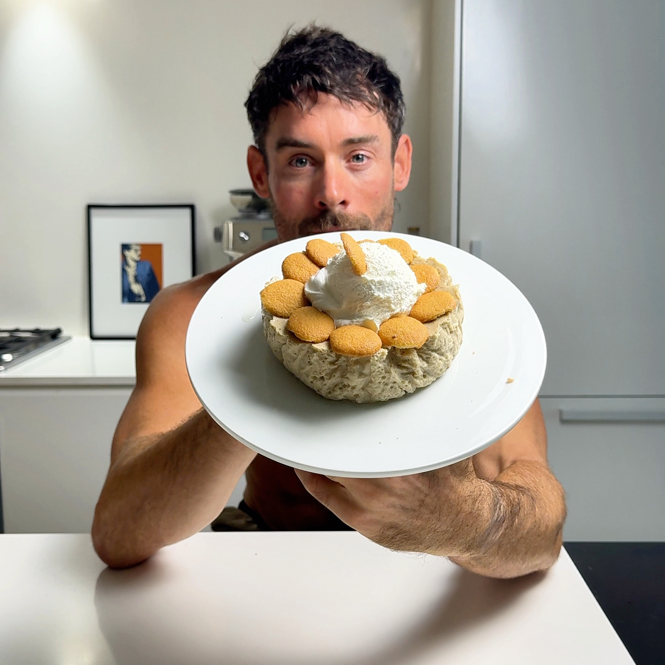 Jacob holding a plate with banana cream cheesecake topped with whipped cream and vanilla wafers.