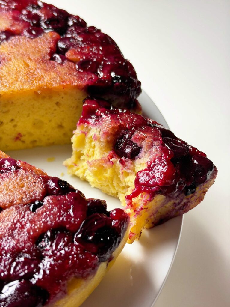 A slice of lemon blueberry upside-down cake pulled away from the whole cake for serving.