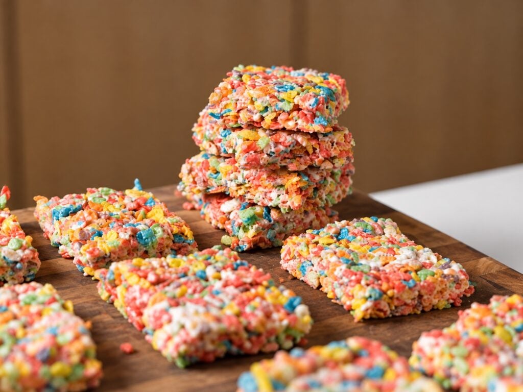 Stack of protein Fruity Pebbles rice crispy treats surrounded by more colorful cereal bars.