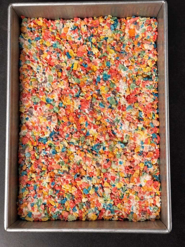 Full metal baking pan filled with pressed protein Fruity Pebbles rice crispy treat mixture.