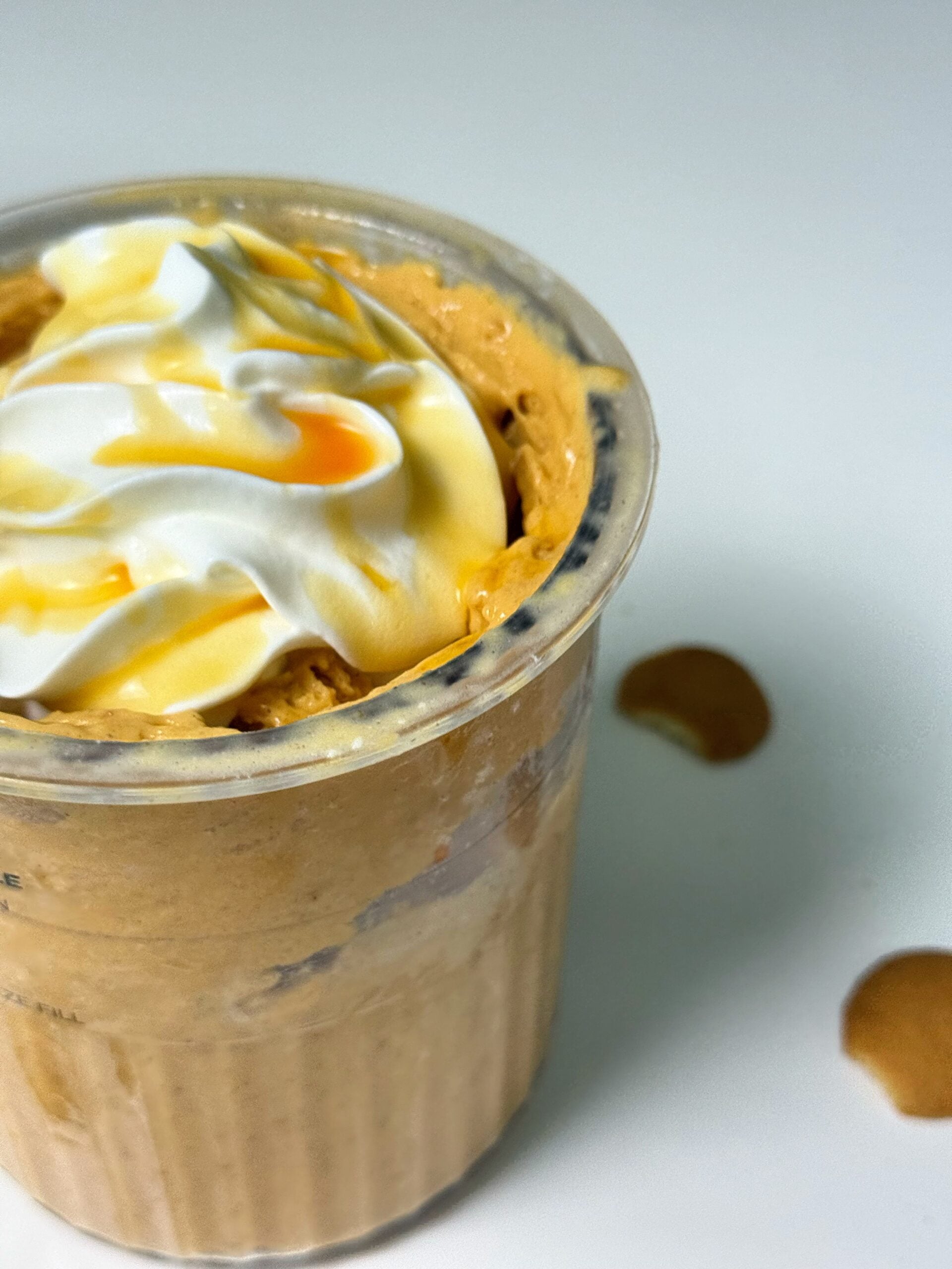 Close-up of pumpkin pie Ninja Creami topped with whipped cream and syrup