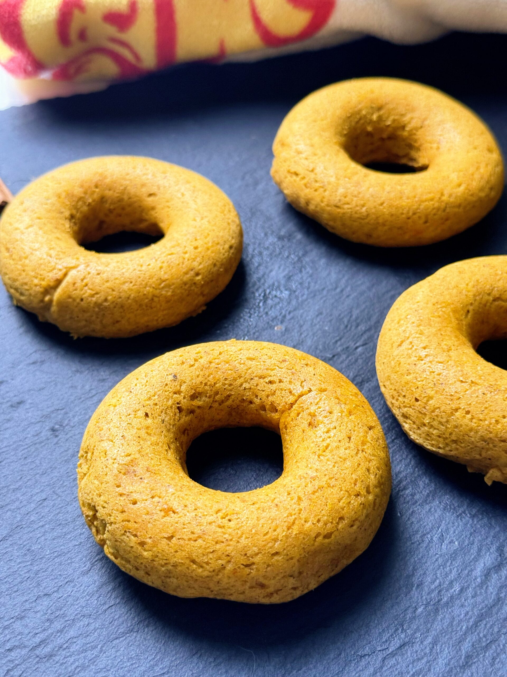 Baked pumpkin spice donuts on a dark slate board