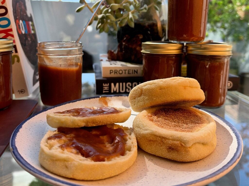 English muffins spread with homemade apple butter beside several filled jars.