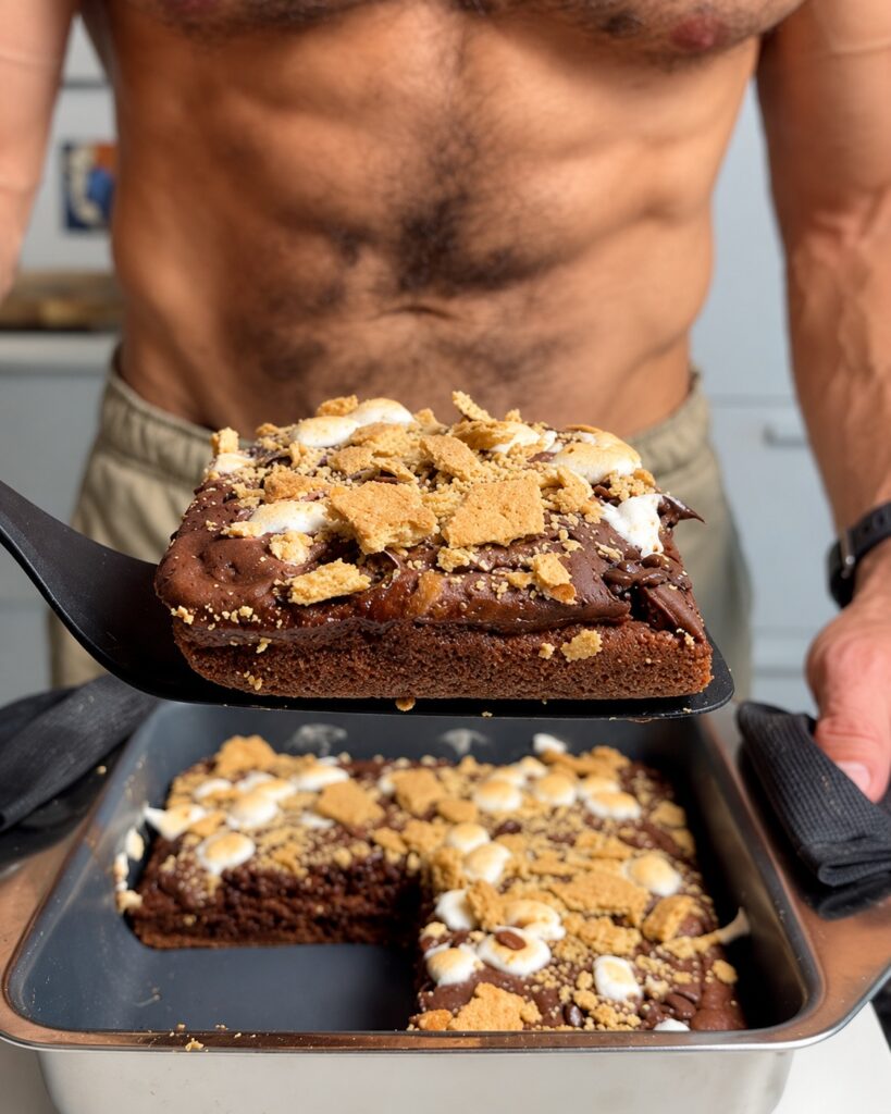 Jacob lifting a large chocolate banana s'mores brownie square from the baking pan with a spatula