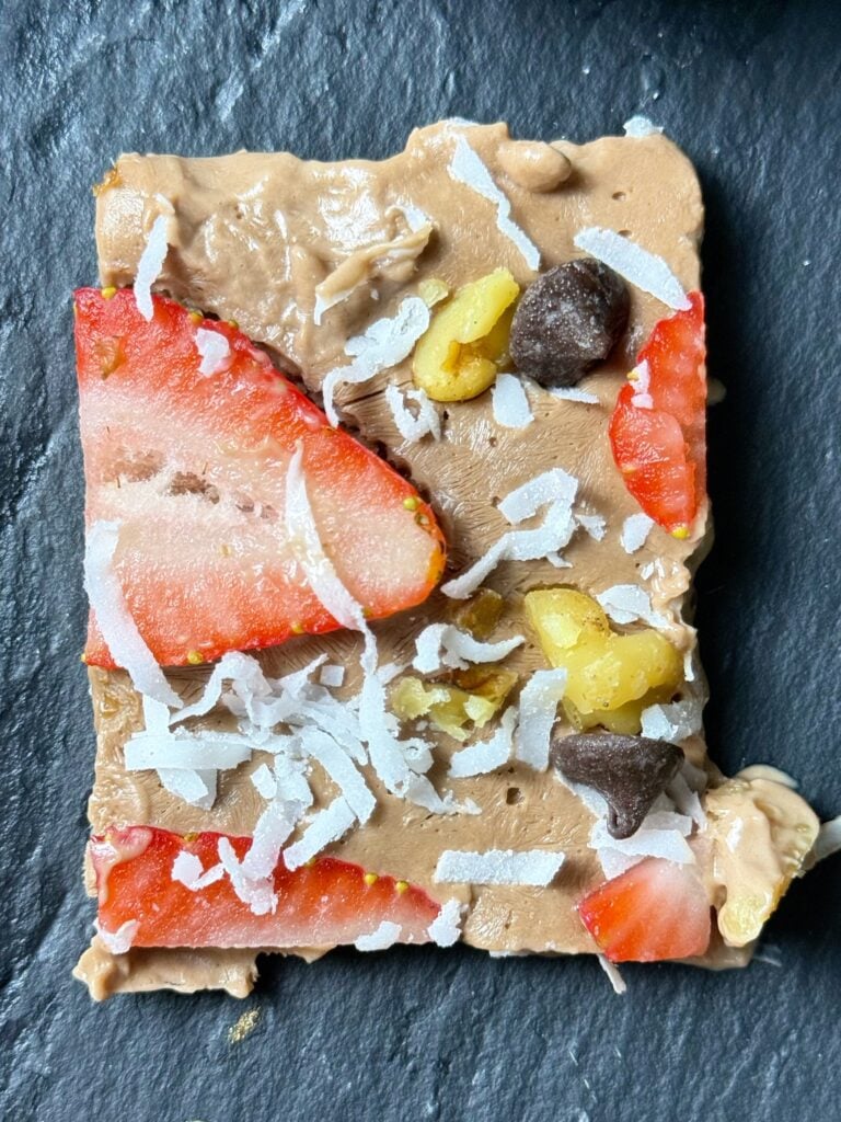 Single square of chocolate Greek yogurt bark with strawberries, walnuts, coconut, and chocolate chips