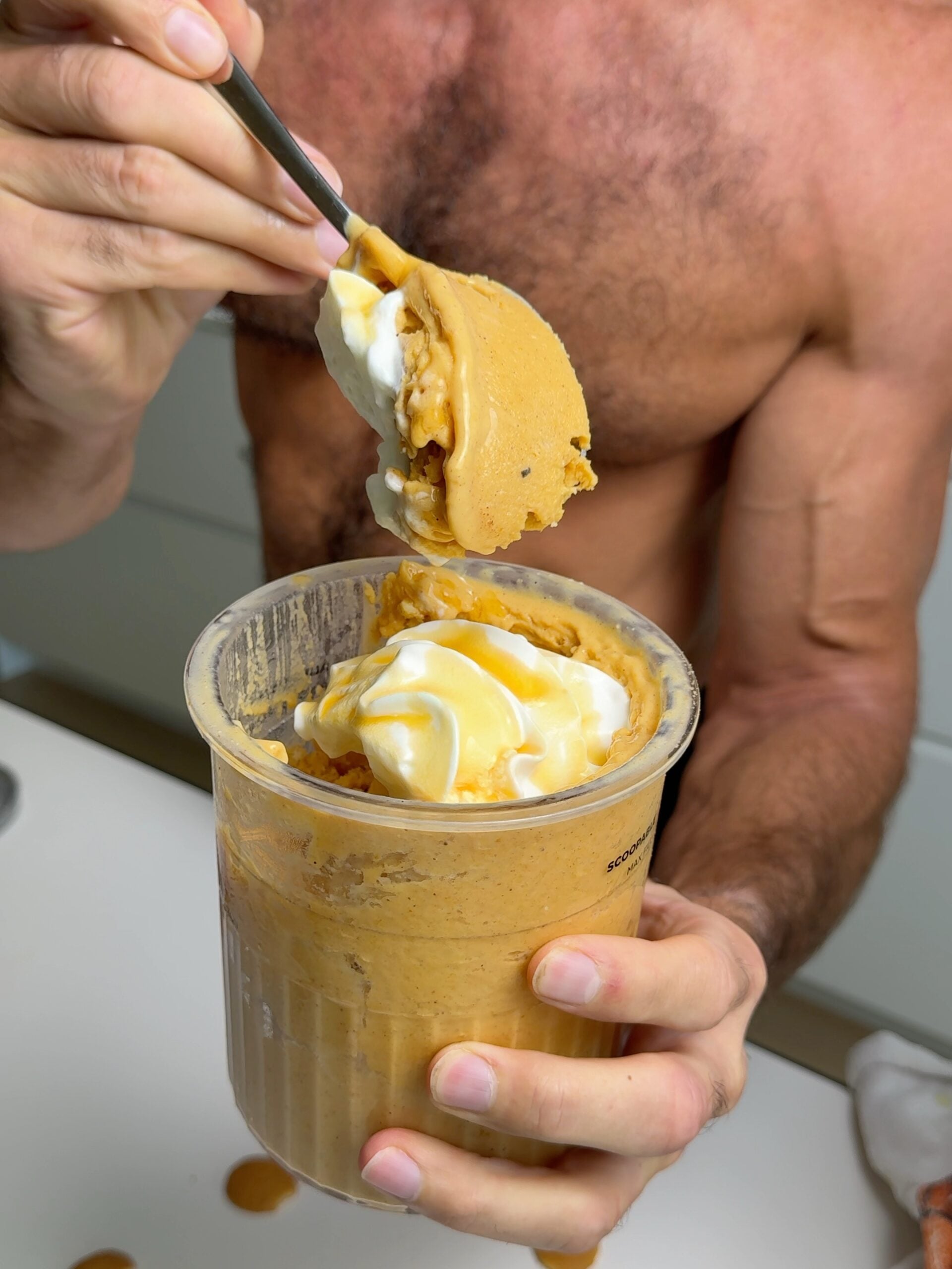 Person lifting a spoonful of pumpkin pie Ninja Creami from the pint container