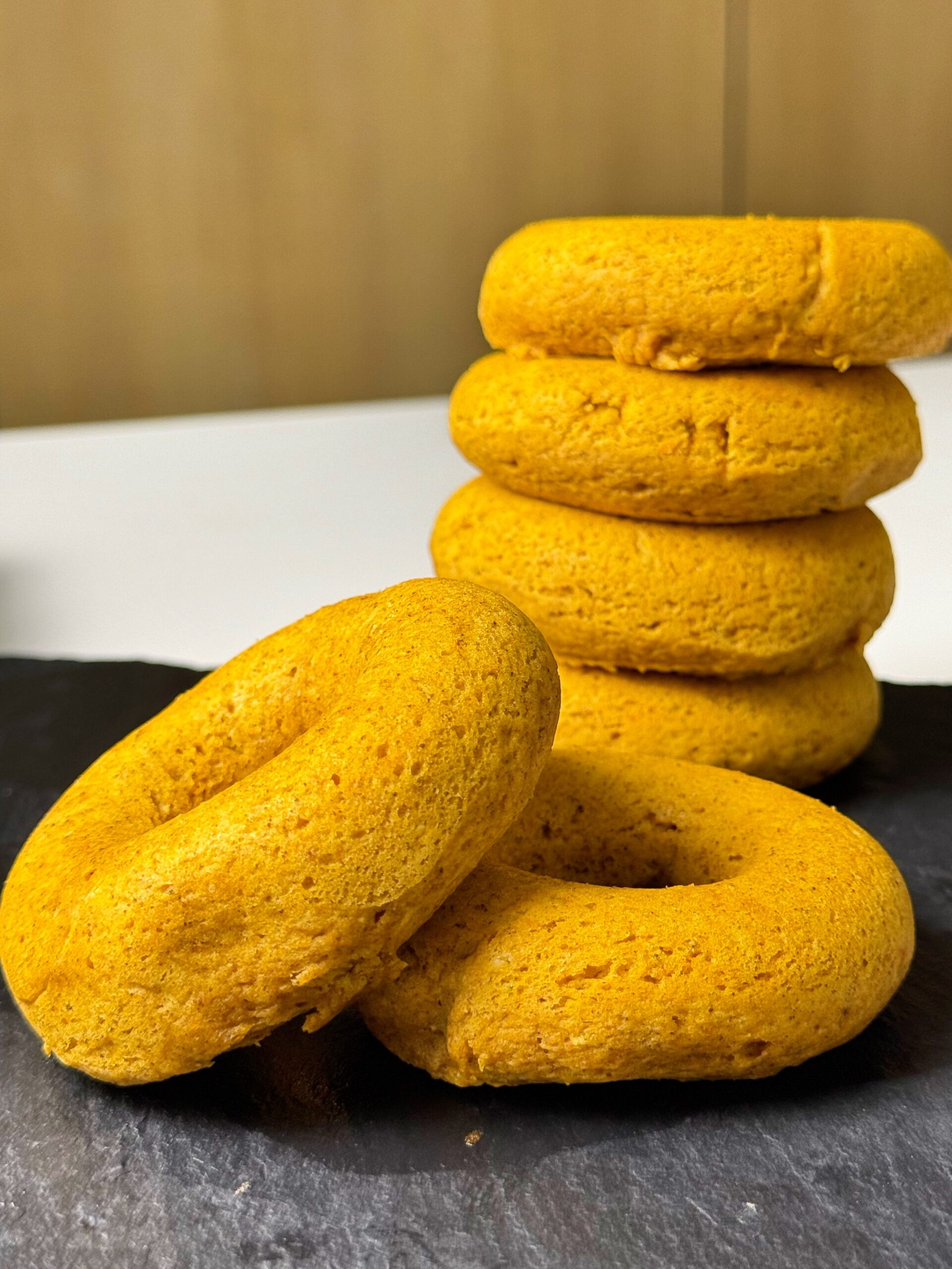 Stack of baked pumpkin spice donuts on a dark board
