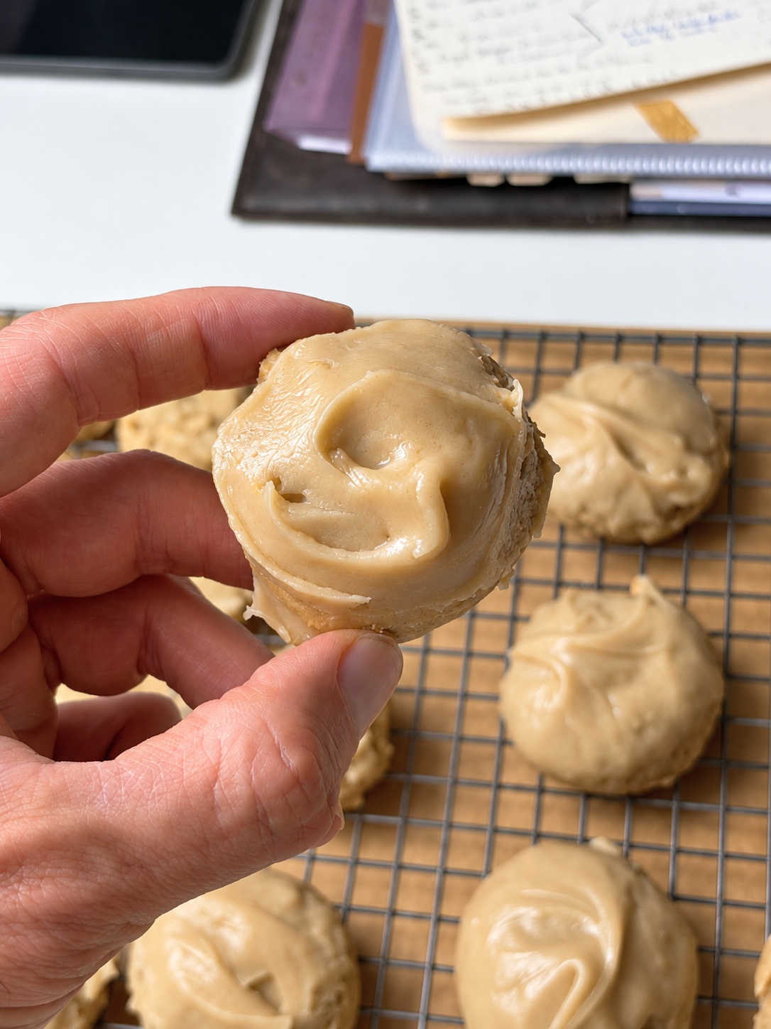 Hand holding a soft brown sugar cookie topped with brown sugar frosting