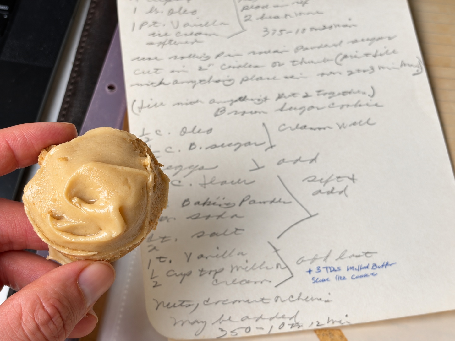 Frosted brown sugar cookie held beside Grandma’s handwritten recipe card