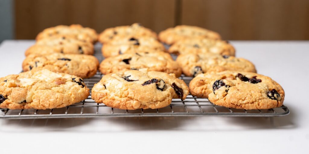 Gluten-free white chocolate cherry almond cookies cooling on a wire rack from a low angle.