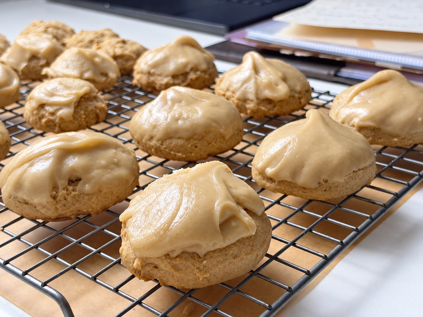 Batch of Grandma’s brown sugar cookies topped with boiled brown sugar frosting on a cooling rack