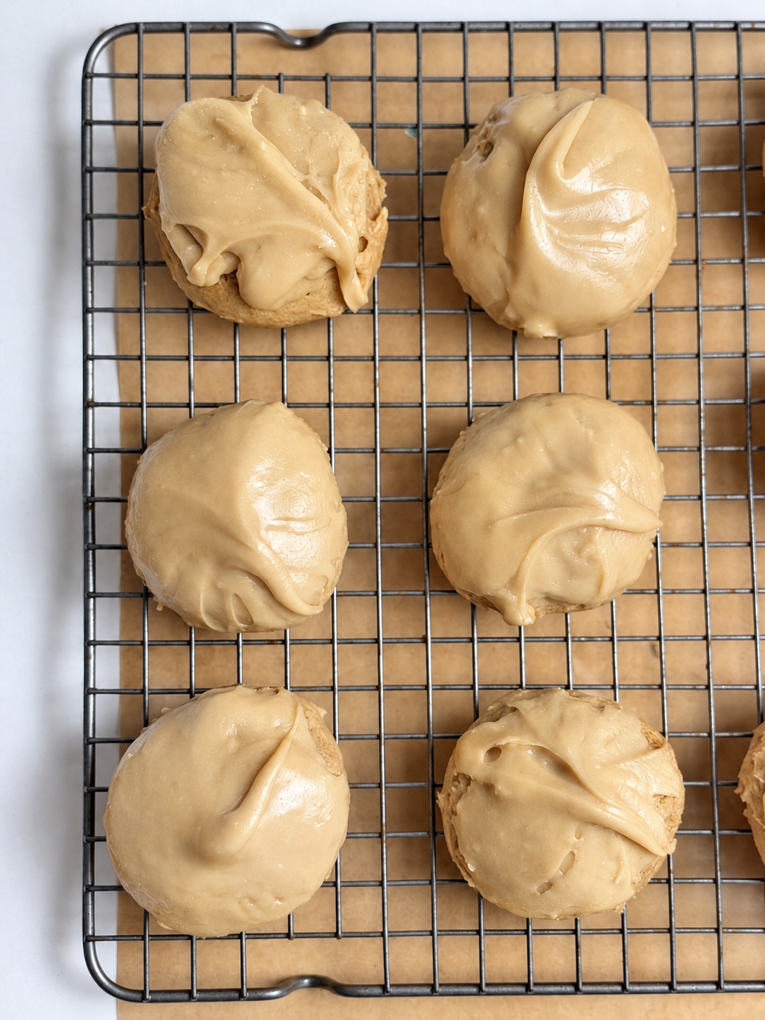 Overhead view of soft brown sugar cookies with brown sugar frosting on a cooling rack