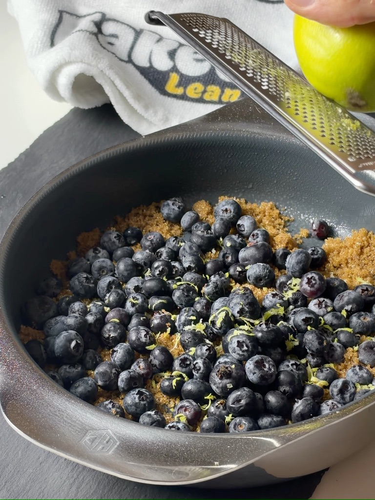 Blueberries and lemon zest in a HexClad pan during recipe preparation