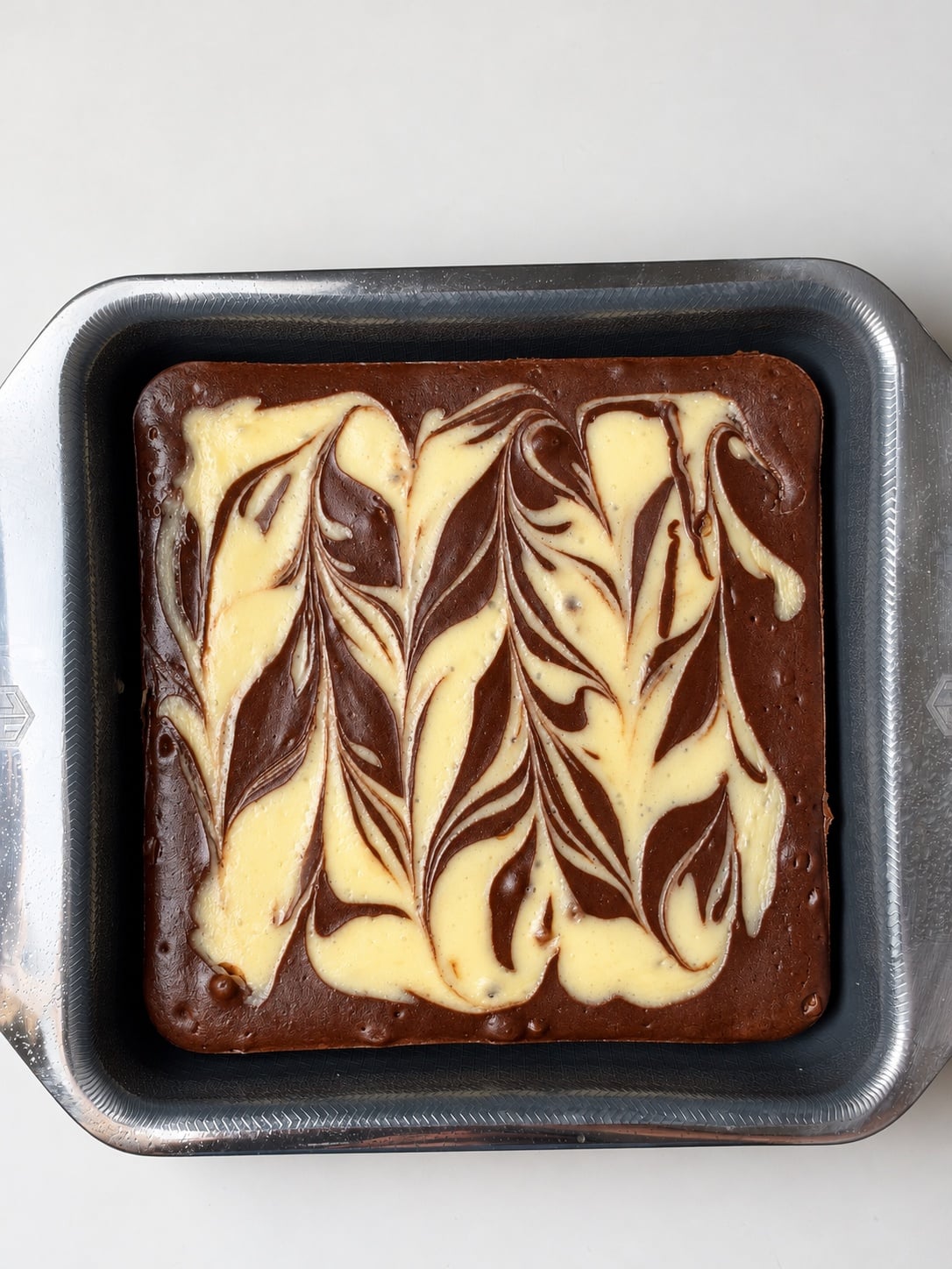 Baked chocolate protein cheesecake brownies with cream cheese swirl in the pan