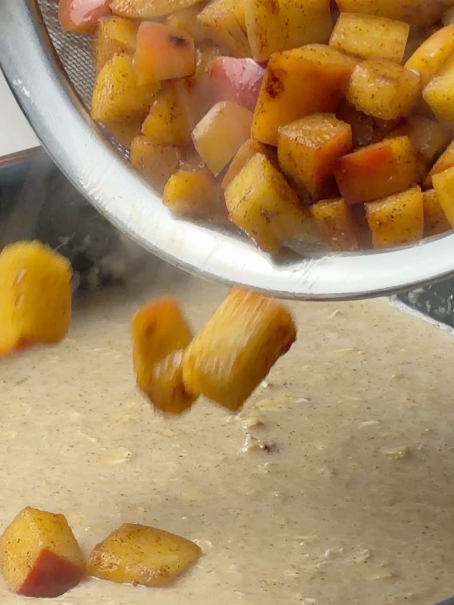 Adding cinnamon-coated diced apples over the baked oatmeal mixture before baking