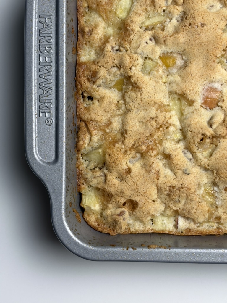 Close-up of golden apple nut squares with chopped apples and walnuts baked into the top.
