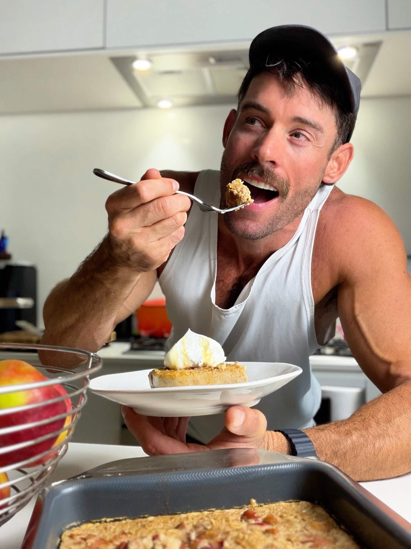 Jacob enjoying a forkful of high-protein apple pie baked oatmeal while holding a plated slice