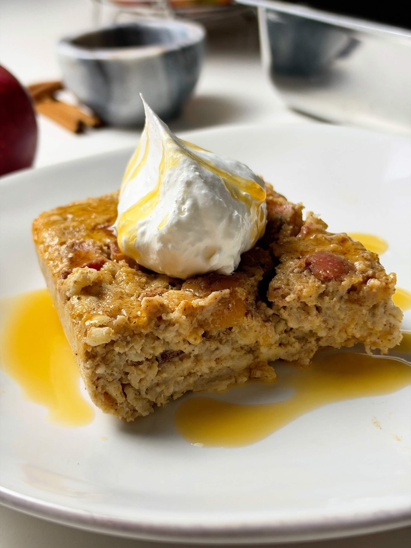 Close-up of a thick apple pie baked oatmeal slice topped with yogurt, cinnamon apples, and syrup